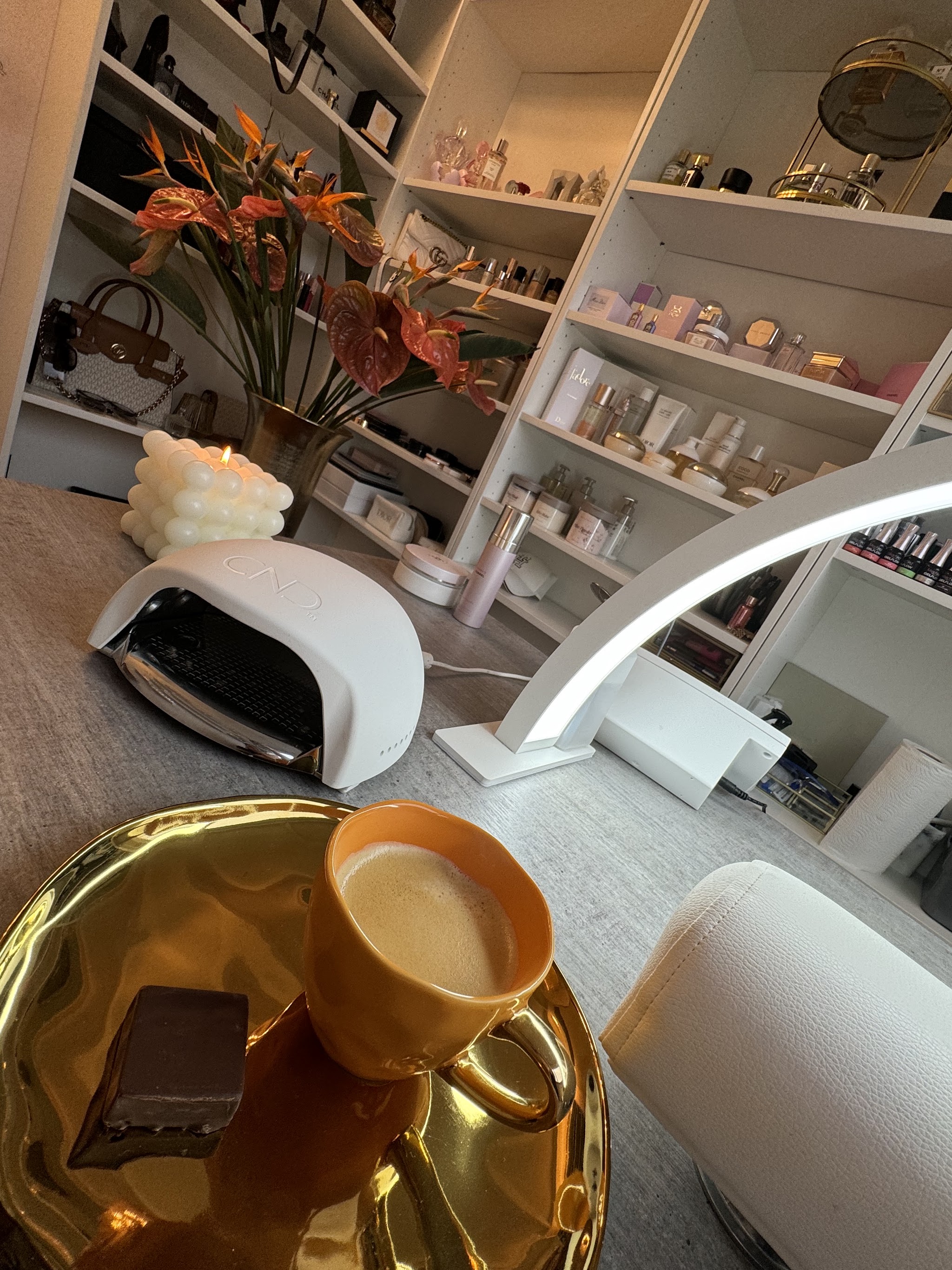 Behandeltafel met nagellamp en een espresso met een bonbon op een gouden schaaltje