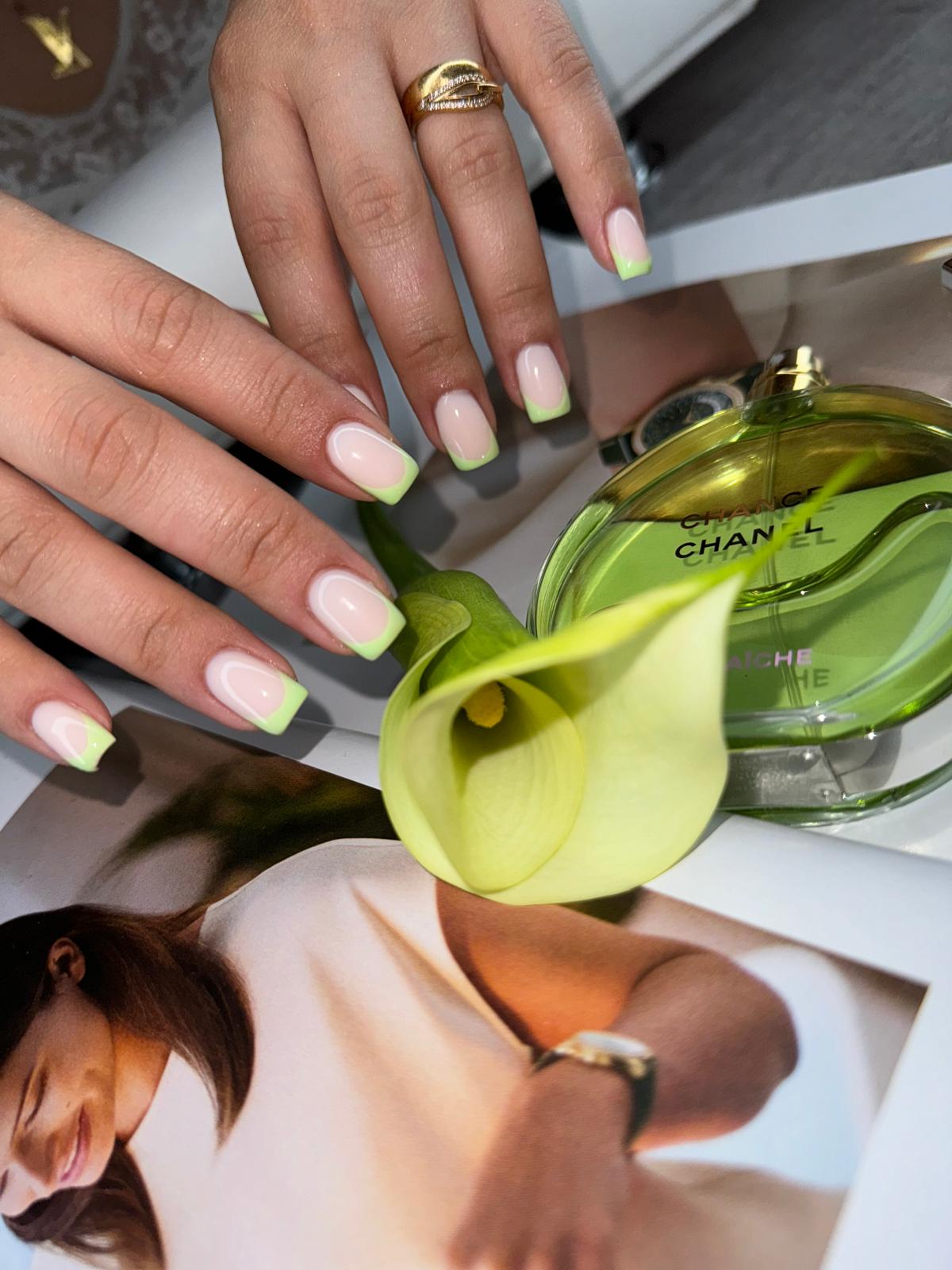 French tip nagels met een limoengroene tip, handen over een bloem