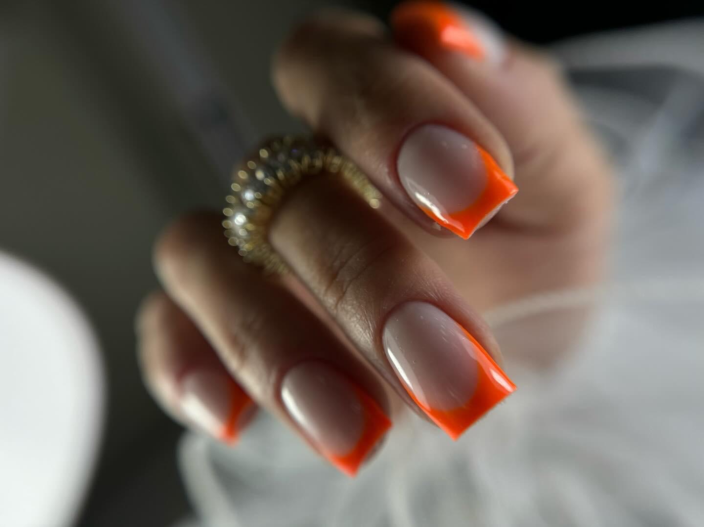 Vierkante nagels met een feloranje French tip en een glinsterende ring
