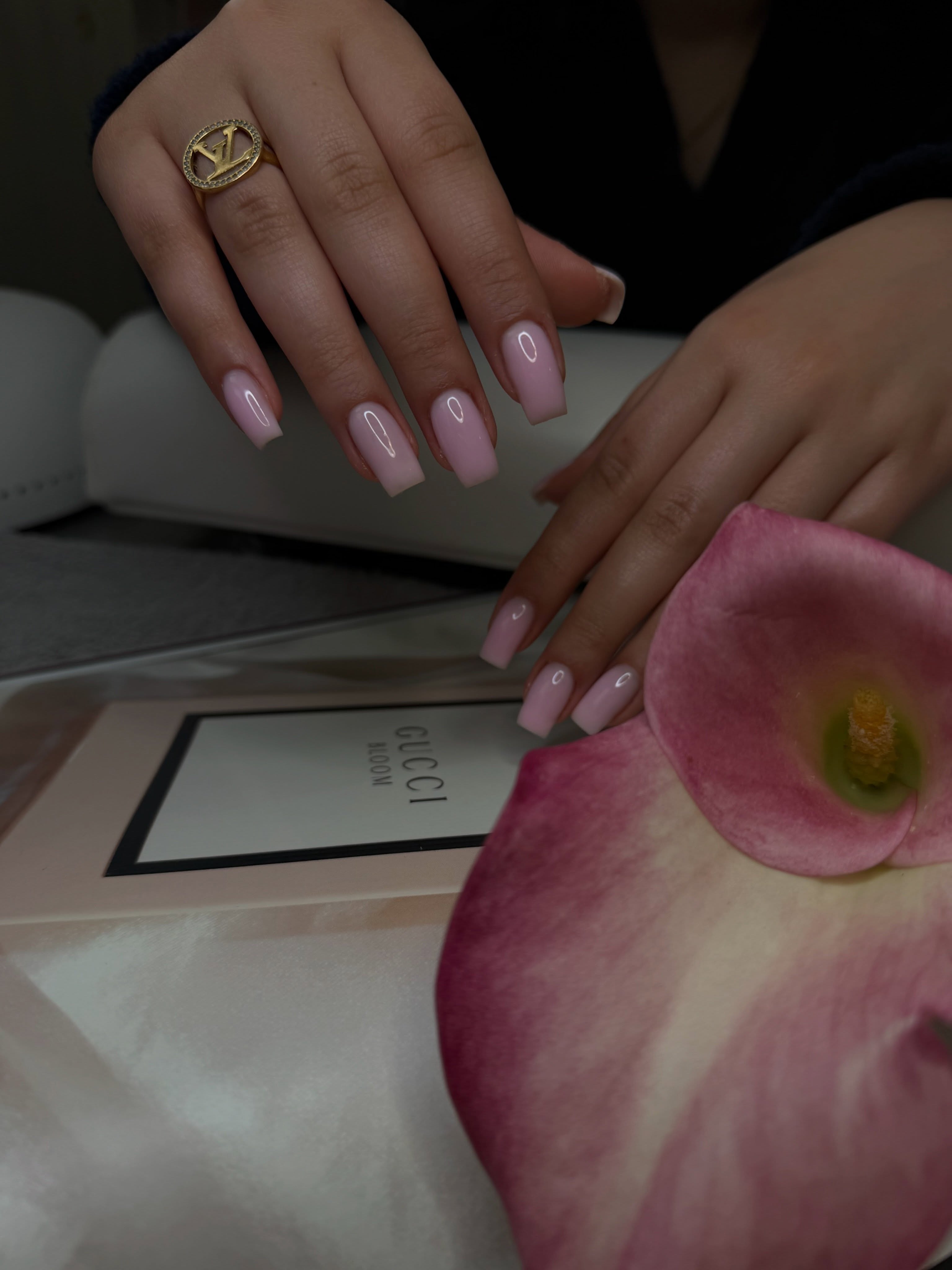 Lange roze square nagels naast een roze callalelie
