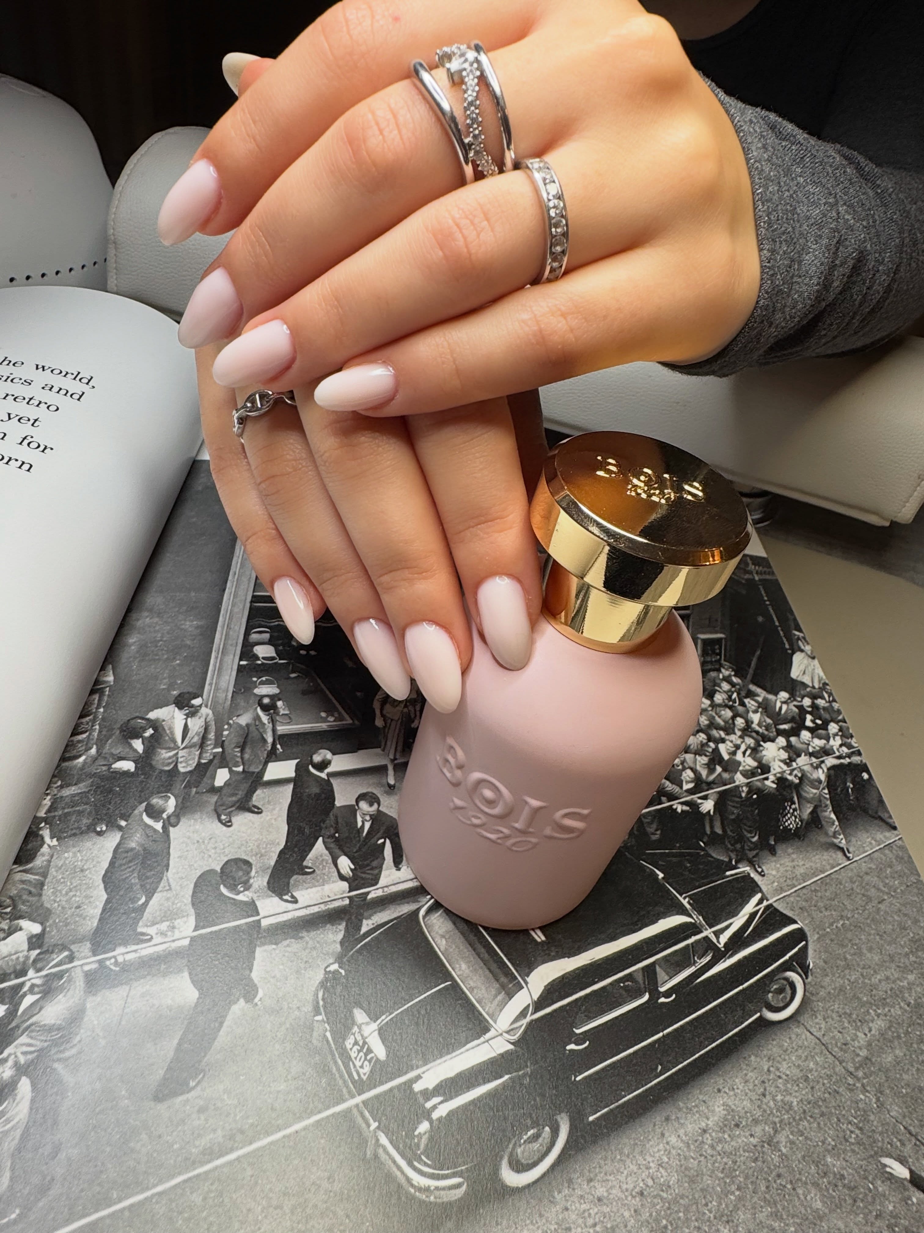 Zachte nude almond nagels, handen over elkaar met ringen